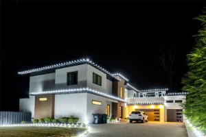 A modern house is beautifully illuminated with white decorative lights at night