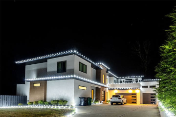 A modern house is beautifully illuminated with white decorative lights at night