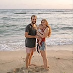 Couple with a baby on the beach enjoying the serene waves and sharing reviews of their experience