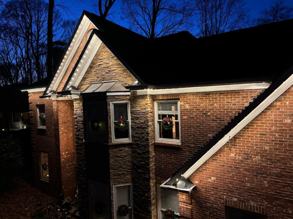A cozy house is illuminated by soft lights at twilight, surrounded by trees