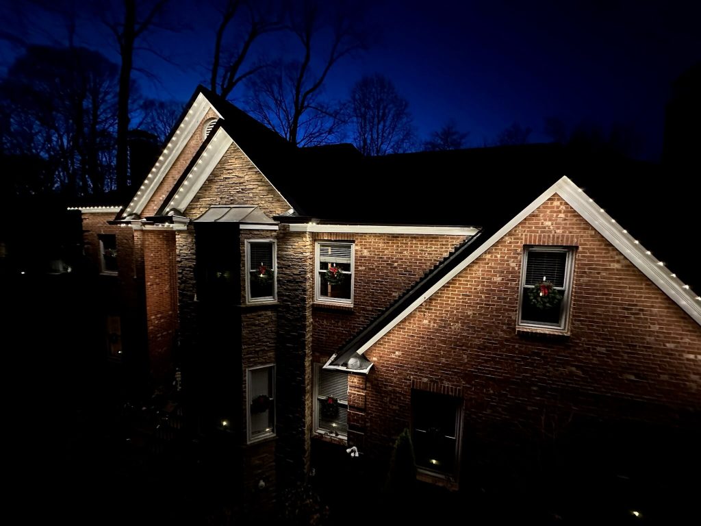 A cozy brick house is softly illuminated against a darkening sky at dusk