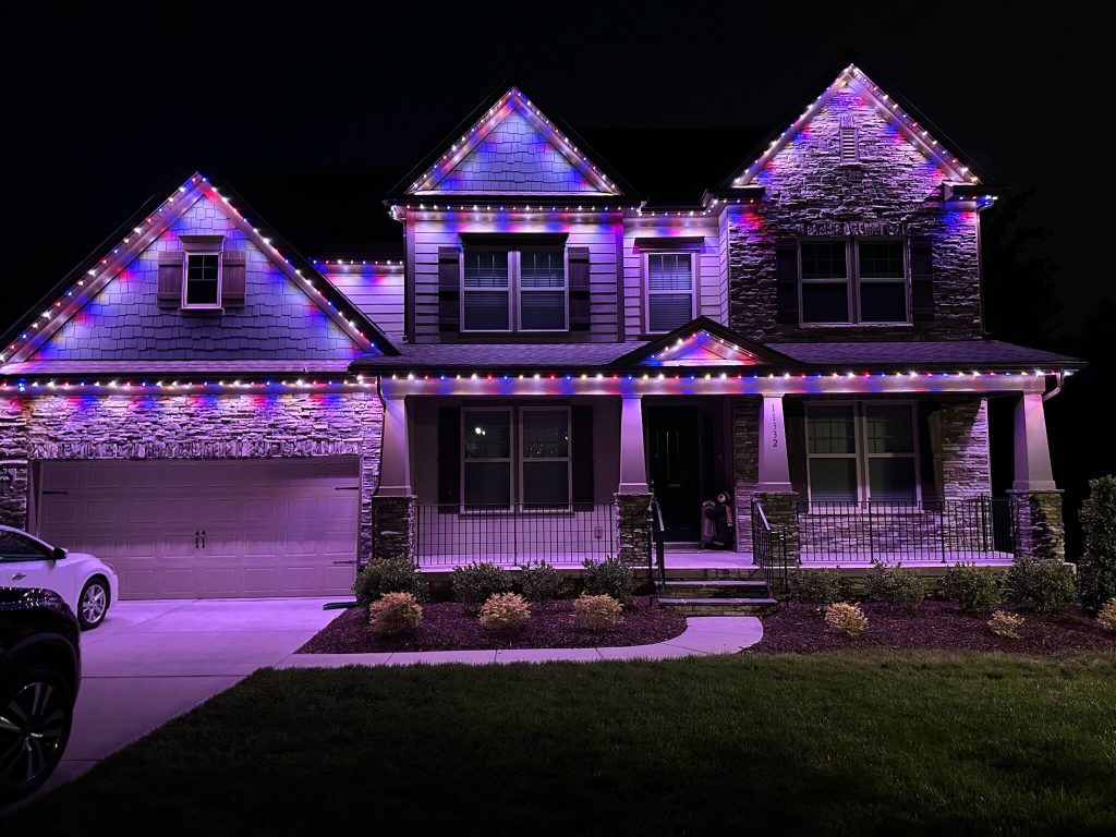 A beautifully lit house is adorned with colorful holiday lights at night