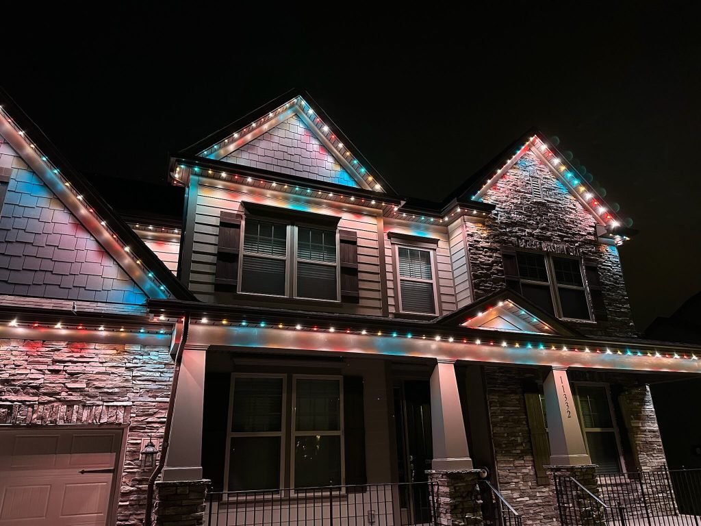 A beautifully lit house adorned with colorful string lights gleams at night