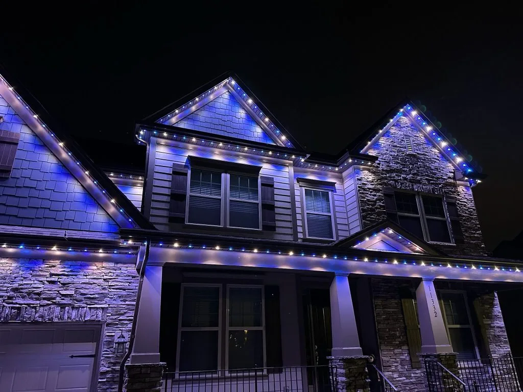A house is illuminated with blue and white string lights at night