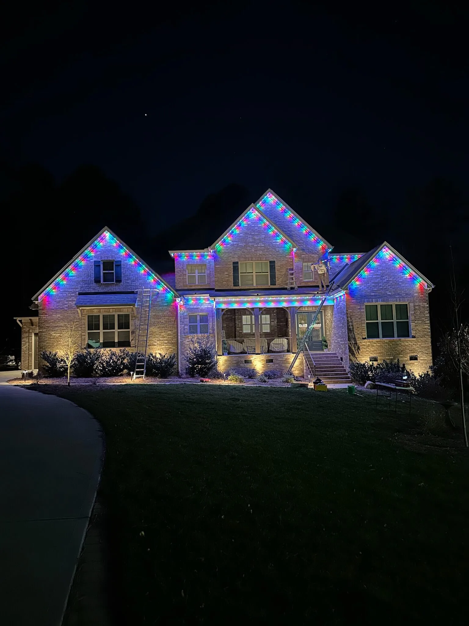 A beautifully decorated house glows with colorful lights against a dark night sky