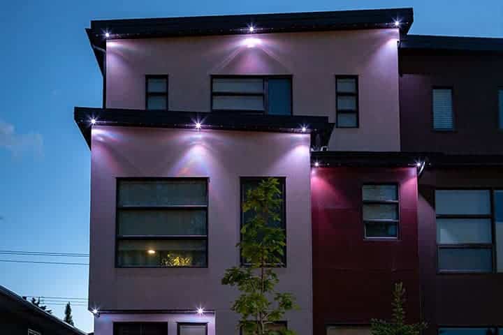 Modern multicolored lights illuminate the facade of a contemporary building at dusk