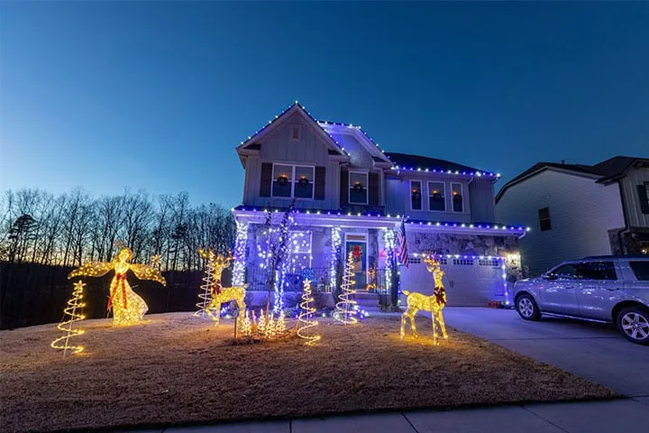 A beautifully decorated house is illuminated with colorful holiday lights and figures