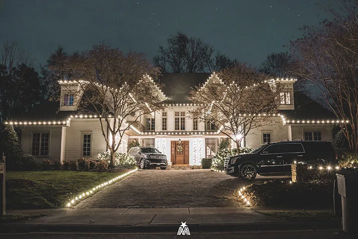 A beautifully decorated house gleams with festive lights under a dark night sky
