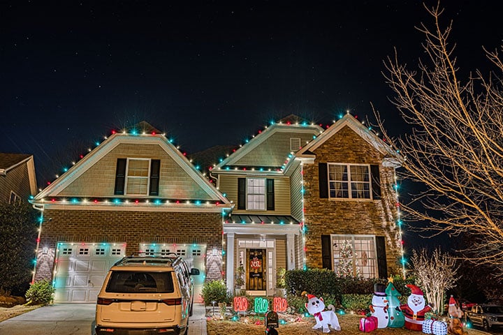 A house is brightly decorated with festive lights and inflatable decorations for the holiday season