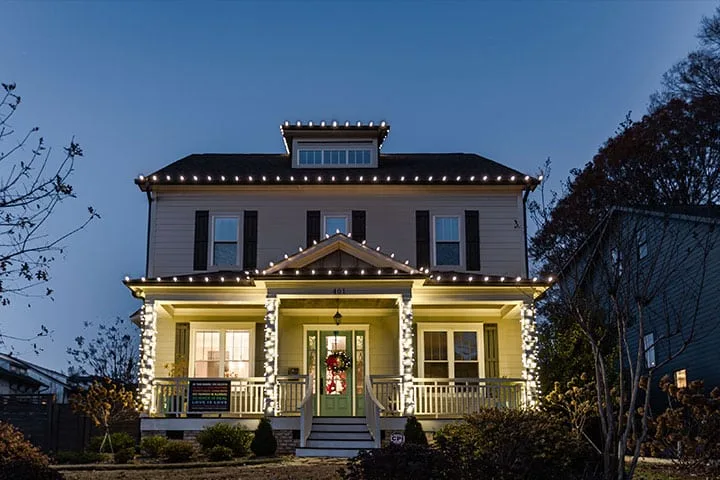 A beautifully decorated house is illuminated with festive lights at dusk