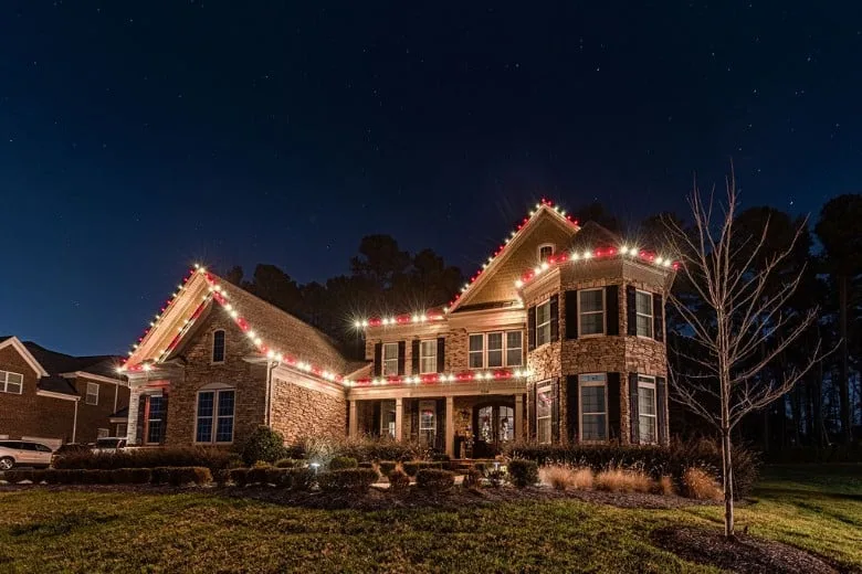 A beautifully decorated house glows with festive lights against the night sky