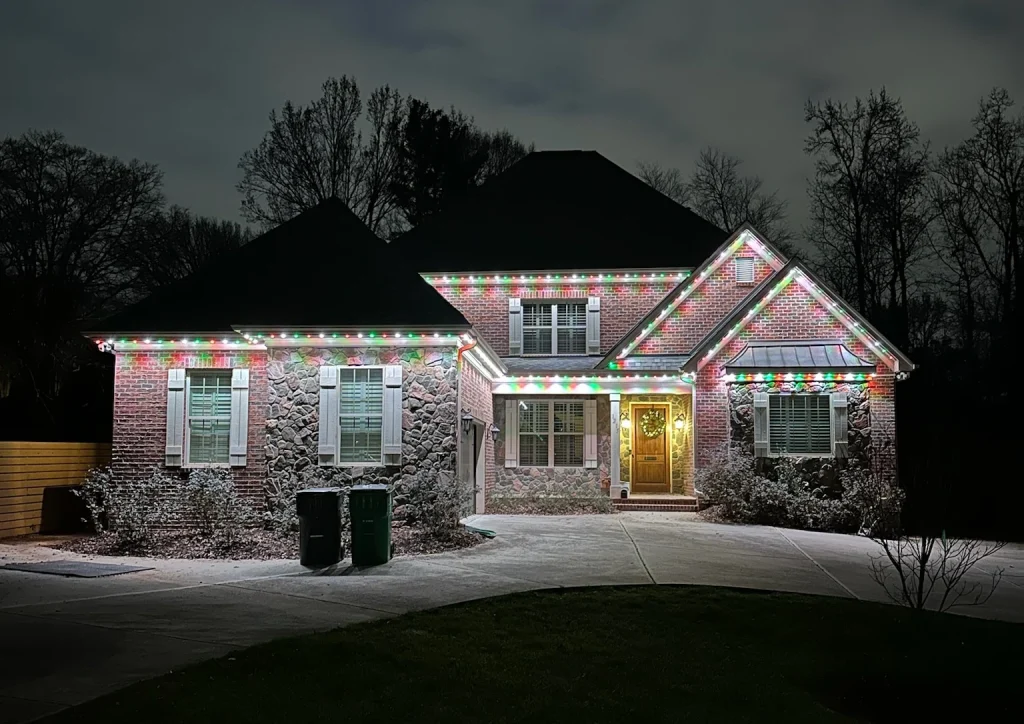 A charming house is illuminated with festive holiday lights against a dark sky