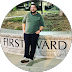 A person stands casually beside a stone sign labeled "First Ward."